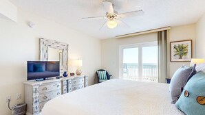 A hotel room with a large bed, a ceiling fan, a television, a dresser, and a window with a view. - Gulf-front condo with balcony, ocean view, W&D, pool, & fitness room (Fort Walton Beach)