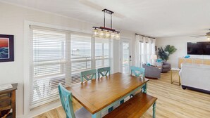 Een ruime woonruimte met een houten eettafel, teal stoelen en een moderne kroonluchter.