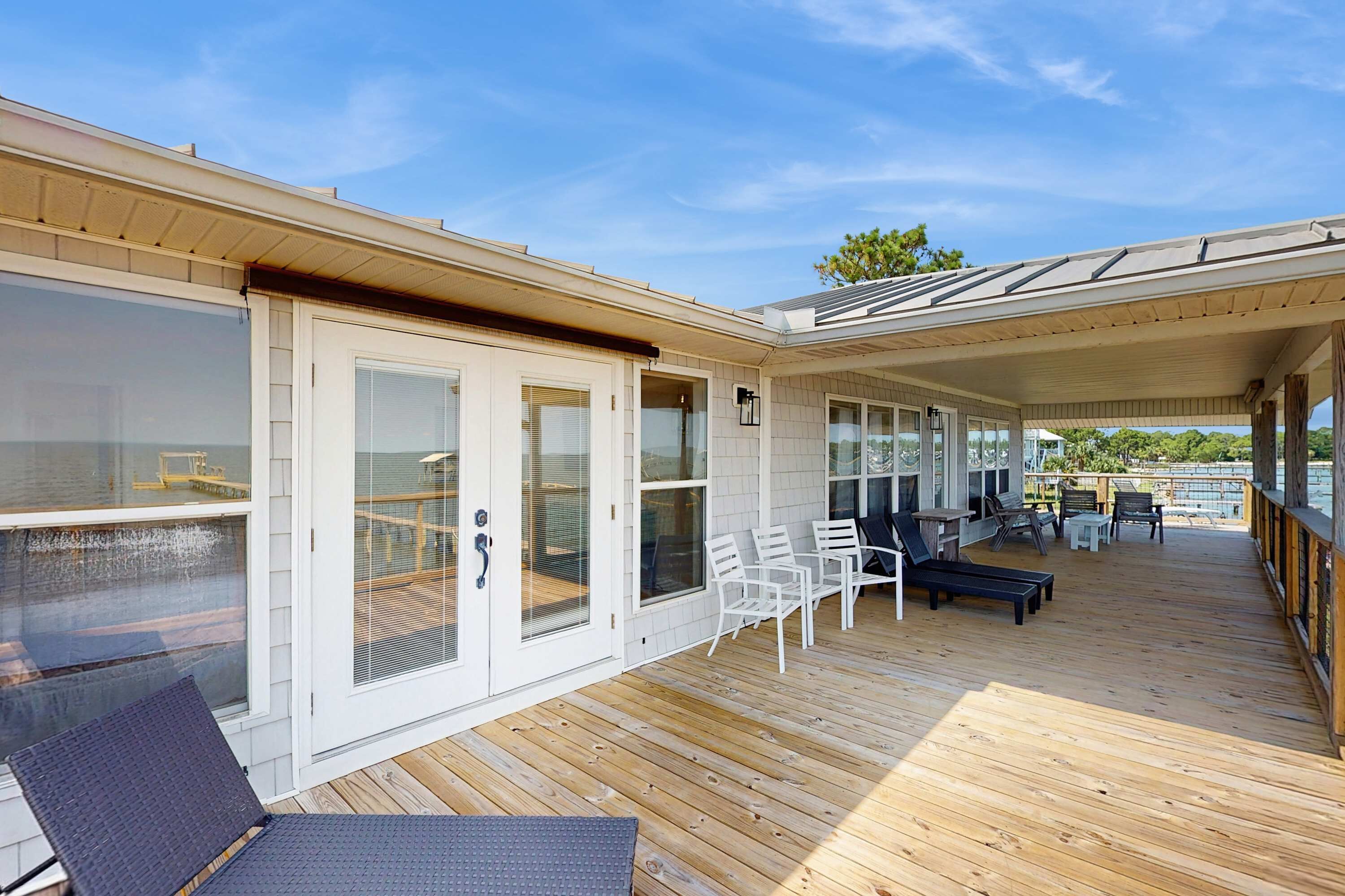 A covered outdoor deck with seating and a view of the water.