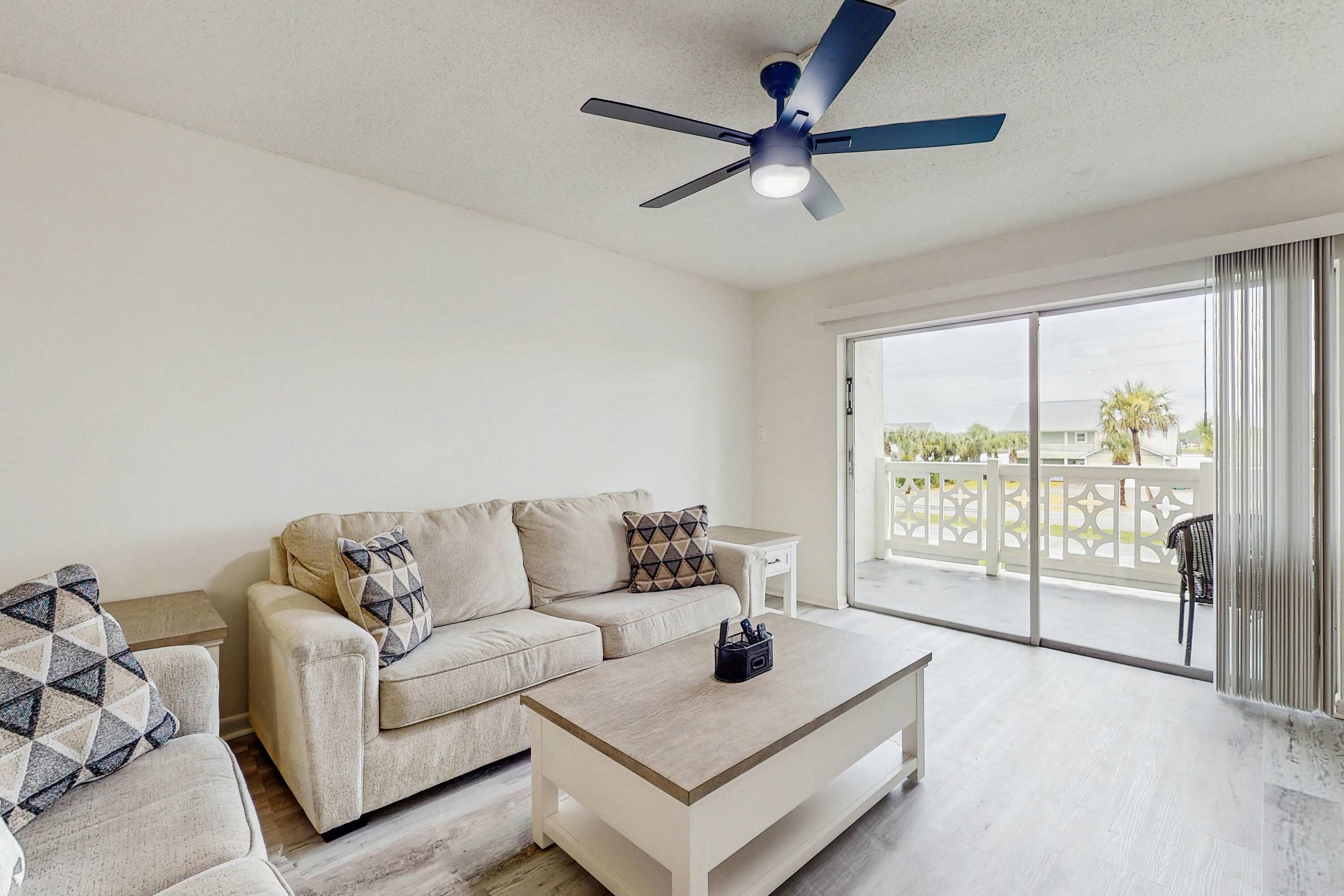 A living room with a beige sofa, a coffee table, and a ceiling fan.