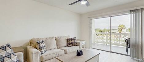 A living room with a beige sofa, a coffee table, and a ceiling fan.