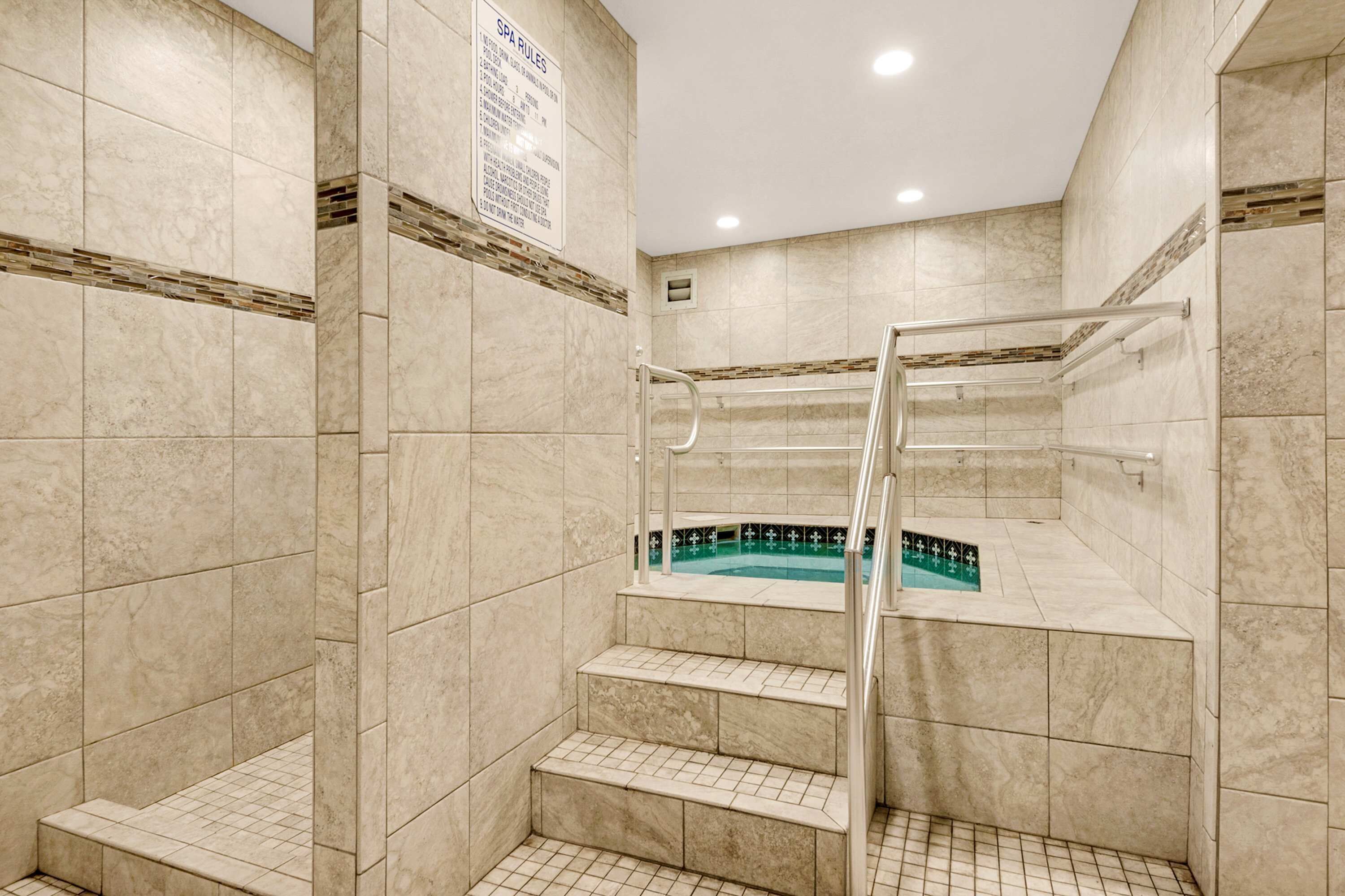 Un espace de bien-être comprenant une piscine, des murs carrelés et un panneau indiquant les règles à respecter dans cet espace.