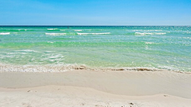 Ein Strand mit klarem türkisblauem Wasser und einem sandigen Ufer.