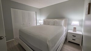 Une chambre à coucher avec un lit, des tables de chevet, une lampe et une armoire.