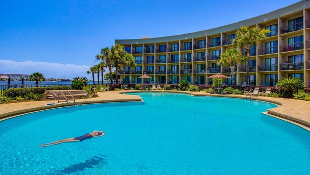 Un hôtel doté d’une grande piscine, de palmiers et offrant une vue sur l’océan.