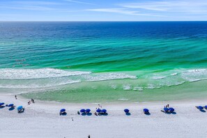 A beach with clear turquoise water, white sand, and blue umbrellas. - Luxe dog-friendly home - pool access & 5-minute walk to beach (Miramar Beach)