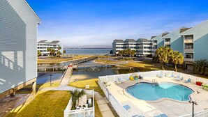 Un hotel con piscina, vistas al agua y un muelle.