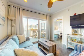 Uma sala de estar moderna com sofá, mesa de centro e televisão, integrada a uma varanda com mobiliário externo.