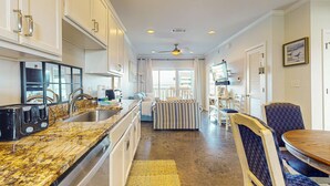 Una cocina moderna con encimeras de granito, electrodomésticos de acero inoxidable y un comedor con una mesa redonda y sillas a rayas.