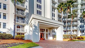 A multi-story hotel with a central entrance, balconies, and palm trees. - Ideal getaway near the beach & golf with shared pool, central AC (Miramar Beach)