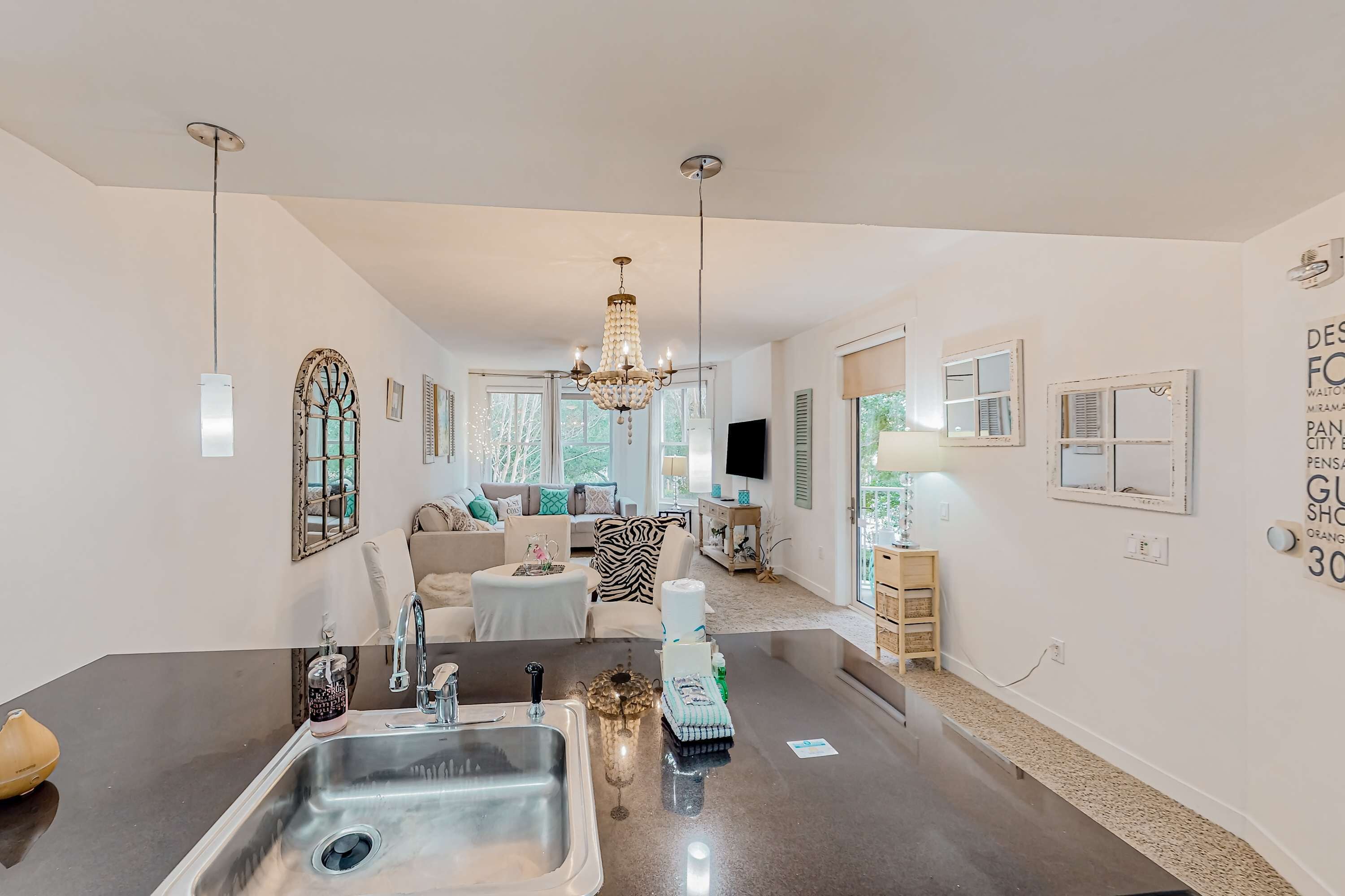 A modern kitchen with a central island, stainless steel sink, and pendant lighting.