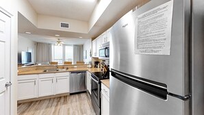 Una cocina moderna con electrodomésticos de acero inoxidable, armarios blancos y piso de madera.