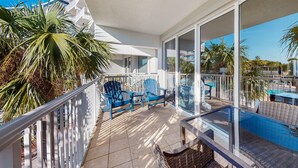 Ein Balkon mit blauen Stühlen, einem Pool und Palmen.