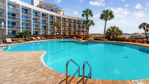 Um hotel com piscina, espreguiçadeiras e palmeiras.