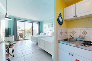 Ein Hotelzimmer mit Balkon, einer Küchenzeile und einem Bett.