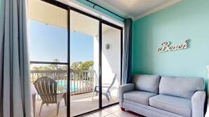 Quarto com porta de vidro deslizante que dá para uma varanda com mobiliário de exterior e piscina.