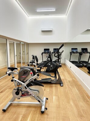 A gym with cardio machines, weight equipment, and a mirrored wall. - Bolhão Luxe | High-End Retreat by the Market (Porto)
