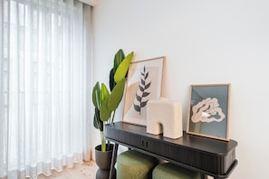 A room with a window, a potted plant, and a console table with framed artwork and a sculpture. - Bolhão Luxe | High-End Retreat by the Market (Porto)