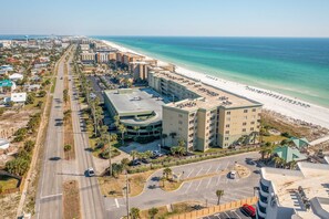 An aerial view of a coastal hotel with a beachfront, a parking lot, and a road leading to the beach. - Beachfront 3rd Floor Condo w Private Balcony, Shared Heated Pool, Beach Access (Fort Walton Beach)