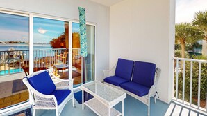 A balcony with wicker furniture, a sofa, and a table. - Second-story waterfront condo with pool view, W/D, AC - perfect location (Pensacola Beach)