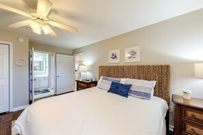 A bedroom with a large bed, a ceiling fan, a nightstand, and a door leading to a bathroom. - 3rd Floor Condo with Shared Pools,Tennis, Private W&D, WiFi, and Central AC (Miramar Beach)