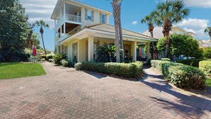 A two-story house with a balcony, surrounded by palm trees and well-maintained gardens. - Gorgeous coastal home with plenty of space with shared pool & beach access (Miramar Beach)