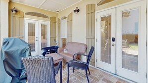 A covered patio area with wicker furniture, a grill, and a sliding glass door. - Gorgeous coastal home with plenty of space with shared pool & beach access (Miramar Beach)