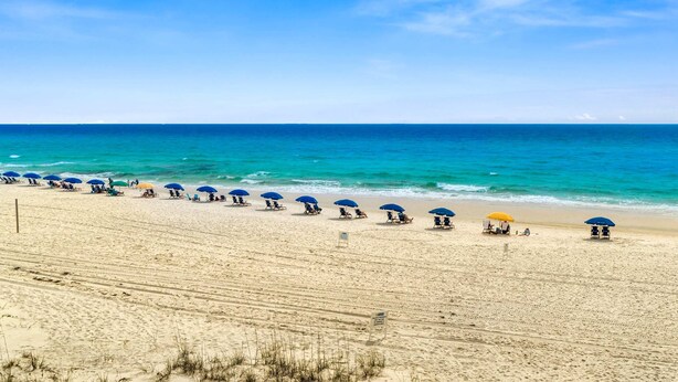 A beach with rows of sun loungers and umbrellas, a clear sky, and the ocean in the background. - Koko Kabana in Hidden Palms (Miramar Beach)