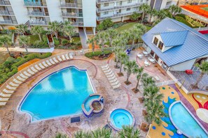 A hotel with a large pool area, multiple lounge chairs, and a small water slide. - Gulf-front condo with pool, hot tub & included beach service (Miramar Beach)