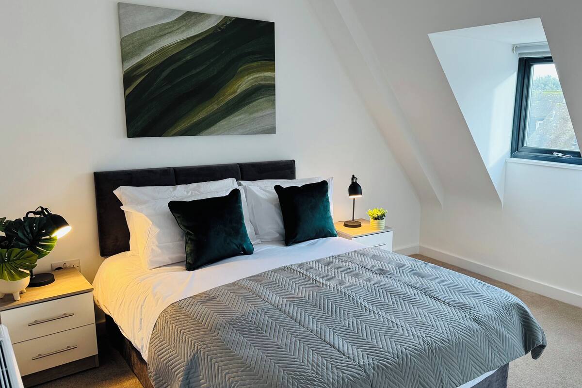 Une chambre à coucher moderne avec un lit, des tables de chevet, une lampe et une fenêtre.