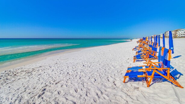 A beach with rows of blue and orange beach chairs and a clear blue sky. - Cozy condo w/ a sunroom plus a shared pool & tennis - minutes from the beach (Miramar Beach)