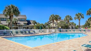 A swimming pool with lounge chairs and palm trees. - Cozy condo w/ a sunroom plus a shared pool & tennis - minutes from the beach (Miramar Beach)