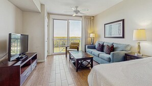 Una camera d'albergo con balcone, televisione, divano, tavolino e letto.