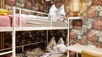 Ein Etagenbett mit Blumenmuster, ein Nachttisch mit Lampe und ein Sessel.