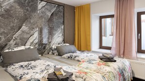 A hotel room with a marble accent wall, two beds with floral bedding, a window with curtains, and a radiator. - Apartment Vierjahreszeiten Herbst – Spacious Family Retreat in Bad Langensalza (Bad Langensalza)