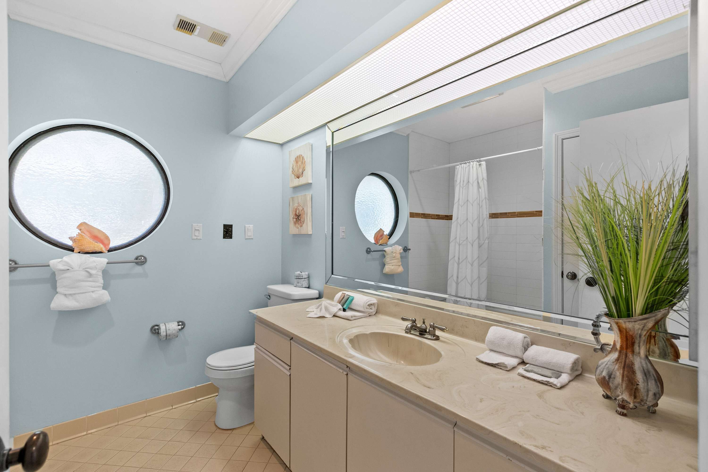 A modern bathroom with a large mirror, a sink, a toilet, and a shower area.