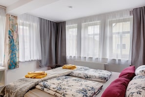 Ein Zimmer mit zwei Betten, einem Heizkörper und einem fensterbepflanzten Fenster.