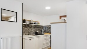 Eine Küche mit weißen Schränken, einer Marmor-Spritzschutzleiste und einer Arbeitsplatte mit Kaffeemaschine.