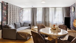 Ein Wohnzimmer mit einer Couch, Sesseln, einem Tisch und einem Fernseher.