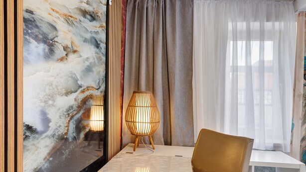Ein Zimmer mit Marmorwand, einem weißen Tisch, einem braunen Stuhl und einer Lampe.