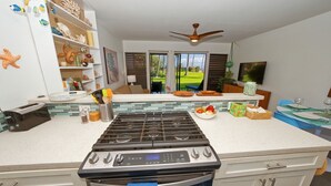 Una cocina moderna con estufa a gas, horno y vistas al exterior a través de amplias ventanas.
