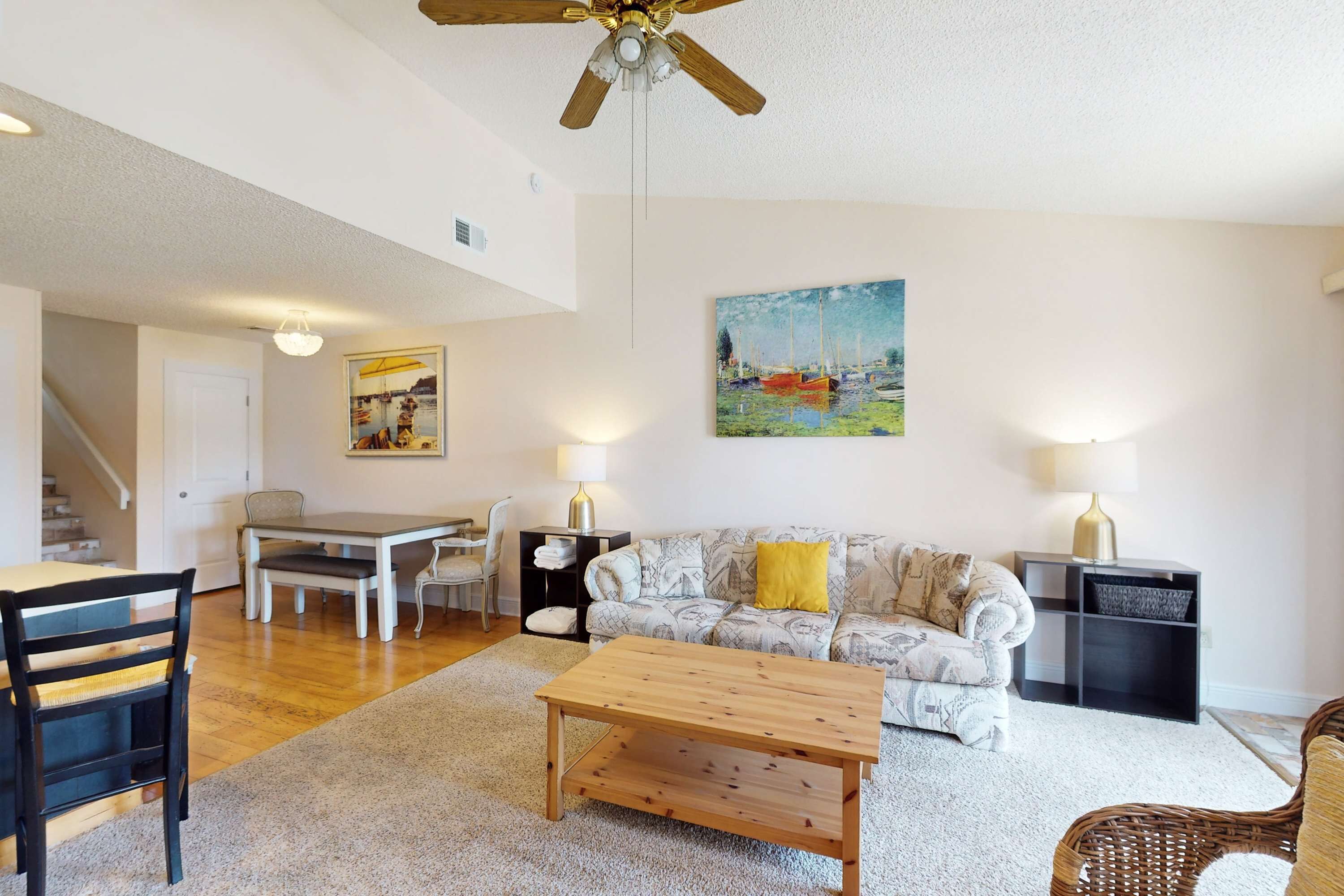 A spacious living area with a wooden coffee table, a patterned sofa, and a dining table with chairs.