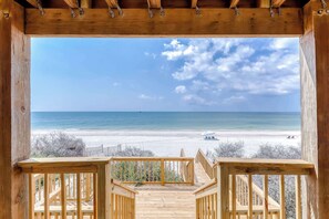 Une terrasse en bois qui mène à un point de vue sur la plage, avec un ciel dégagé.