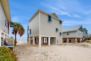 A beachfront house with a covered porch, a palm tree, and a sandy beach in the background. - Spacious & updated waterfront home w decks, beach views & private boardwalk (Cape San Blas)