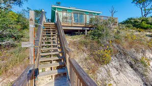 A wooden staircase leading to a turquoise building with a balcony.