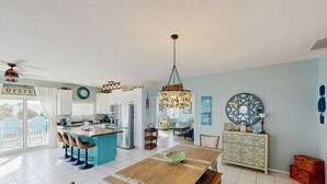 Een ruime keuken met een centraal eiland, een eethoek met een houten tafel, en een zithoek met een bank en stoelen.