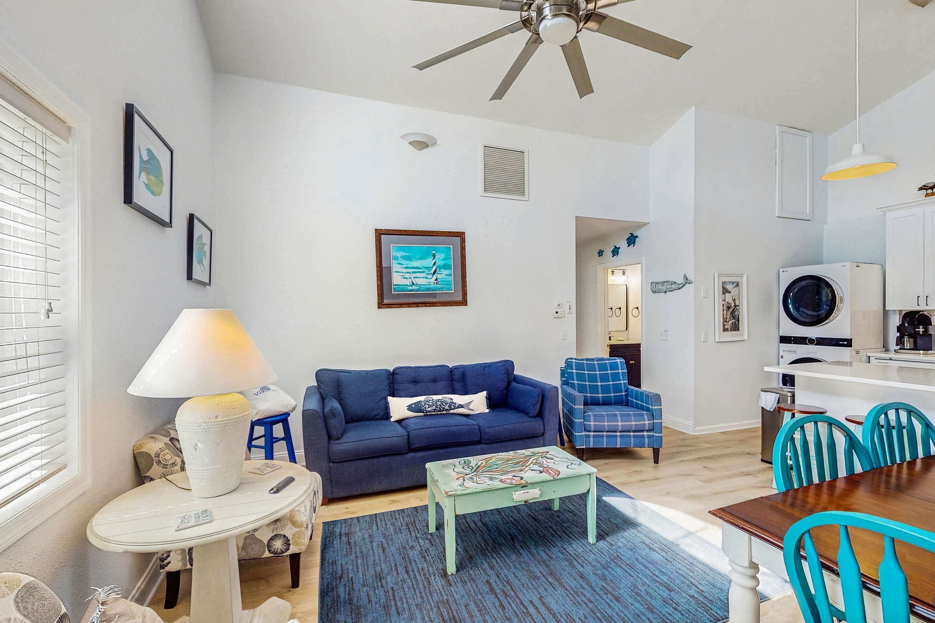A living room with a blue sofa, a coffee table, and a ceiling fan.