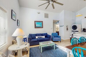 Un salon avec un canapé bleu, une table basse et un ventilateur de plafond.