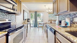 Cozinha moderna com eletrodomésticos de aço inoxidável, painel de azulejos e área de refeições com mesa e cadeiras.