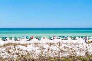 A beach with rows of umbrellas and beach chairs, a clear blue sky, and the ocean in the background. - Beach haven at Maravilla Resort with 2 pools & tennis (Miramar Beach)